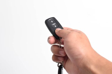 Beyaz arka planda izole edilmiş uzaktan kumandalı bir arabanın anahtarını tutan bir adam. Modern araba anahtarı