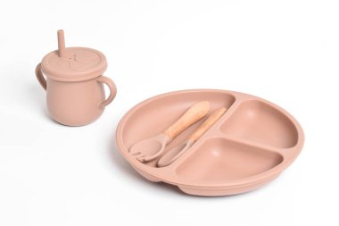 Silikon sofra takımı. Silikon tabağı, fincan, kaşık, çatal. Beyaz arka planda bebek sofra takımı. Bebek maması servisi, bulaşık takımı. İlk bebek maması konsepti