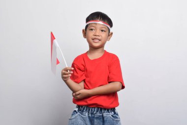 Kırmızı tişörtlü neşeli bir Endonezyalı beyaz arka planda izole edilmiş bir bayrak ve gülümseme taşıyor. Endonezya Bağımsızlık Günü konsepti.