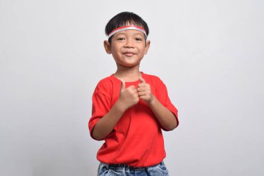 Kırmızı tişörtlü mutlu bir Endonezyalı beyaz arka planda izole edilmiş, baş parmağını kaldırıyor. Endonezya Bağımsızlık Günü konsepti.