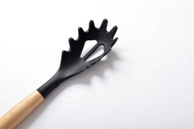 Beyaz arka planda izole edilmiş spagettiyi boşaltmak için siyah plastik kaşığı kapat.