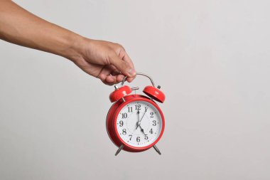 Elinde kırmızı alarmlı saati tutan adam beyaz arka planda izole edilmiş. Kırpma yolu ile yakın plan