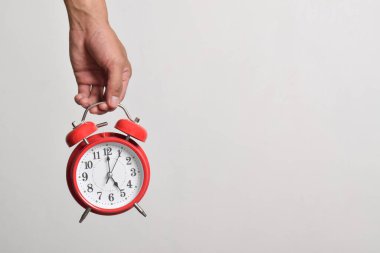 Elinde kırmızı alarmlı saati tutan adam beyaz arka planda izole edilmiş. Kırpma yolu ile yakın plan