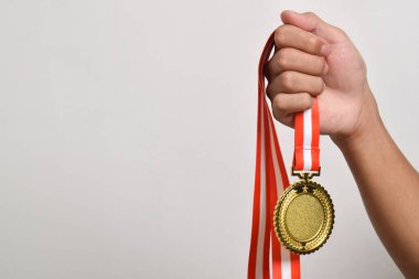 El ele tutuşan altın madalya beyaz arka planda izole edilmiş. Kazanan ve başarılı konsept