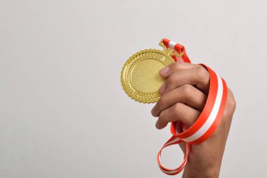 El ele tutuşan altın madalya beyaz arka planda izole edilmiş. Kazanan ve başarılı konsept