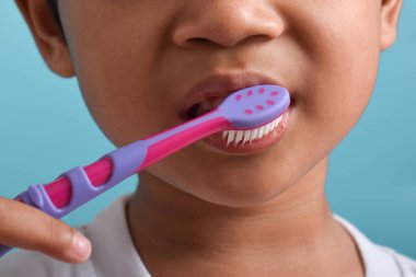 Dişlerini fırçalayan mutlu Asyalı çocuk mavi arka planda izole edilmiş. Çocuk diş sağlığı, tıbbi bakım.