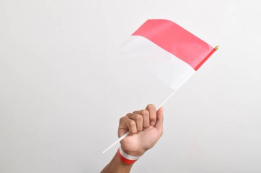 Beyaz arka planda izole edilmiş bir Endonezya bayrağını tutan insan eli. Endonezya 'nın bağımsızlık günü. Ulusal Bayram Günü ve mutlu kutlamalar.