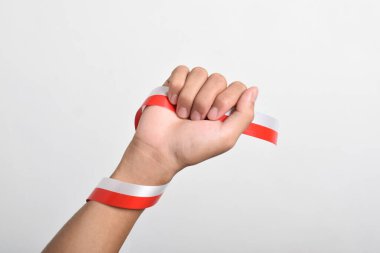 Beyaz arka planda izole edilmiş Endonezya bayrağının sembolü olarak kırmızı ve beyaz kurdeleli bir adamın yumruğu. Endonezya Bağımsızlık Günü konsepti, 17 Ağustos. Boşluğu kopyala