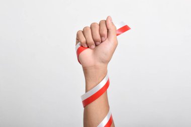 Beyaz arka planda izole edilmiş Endonezya bayrağının sembolü olarak kırmızı ve beyaz kurdeleli bir adamın yumruğu. Endonezya Bağımsızlık Günü konsepti, 17 Ağustos. Boşluğu kopyala
