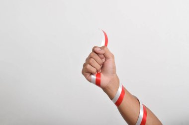 Beyaz arka planda izole edilmiş Endonezya bayrağının sembolü olarak kırmızı ve beyaz kurdeleli bir adamın yumruğu. Endonezya Bağımsızlık Günü konsepti, 17 Ağustos. Boşluğu kopyala