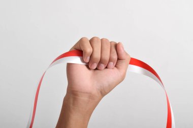 Beyaz arka planda izole edilmiş Endonezya bayrağının sembolü olarak kırmızı ve beyaz kurdeleli bir adamın yumruğu. Endonezya Bağımsızlık Günü konsepti, 17 Ağustos. Boşluğu kopyala