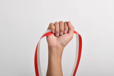 Beyaz arka planda izole edilmiş Endonezya bayrağının sembolü olarak kırmızı ve beyaz kurdeleli bir adamın yumruğu. Endonezya Bağımsızlık Günü konsepti, 17 Ağustos. Boşluğu kopyala