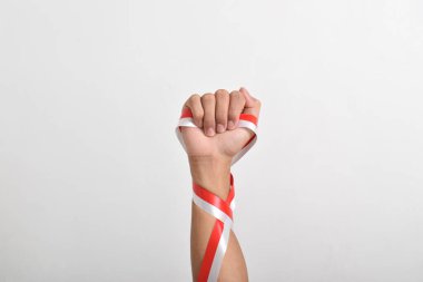 Beyaz zemin üzerinde izole edilmiş kırmızı ve beyaz Endonezya bayrağının sembolü olarak kırmızı ve beyaz kurdeleyi tutan yumruk. 17 Ağustos 'ta Endonezya Bağımsızlık Günü Konsepti. Kopya Boşluğu