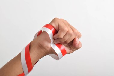 Beyaz zemin üzerinde izole edilmiş kırmızı ve beyaz Endonezya bayrağının sembolü olarak kırmızı ve beyaz kurdeleyi tutan yumruk. 17 Ağustos 'ta Endonezya Bağımsızlık Günü Konsepti. Kopya Boşluğu
