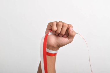 Beyaz zemin üzerinde izole edilmiş kırmızı ve beyaz Endonezya bayrağının sembolü olarak kırmızı ve beyaz kurdeleyi tutan yumruk. 17 Ağustos 'ta Endonezya Bağımsızlık Günü Konsepti. Kopya Boşluğu
