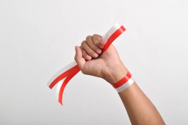 Eller, beyaz arka planda izole edilmiş Endonezya bayrağının bir sembolü olarak kırmızı ve beyaz kurdelelerle sımsıkı sarılmış. Endonezya Bağımsızlık Günü konsepti, 17 Ağustos. Boşluğu kopyala