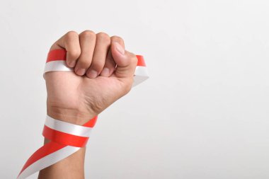 Eller, beyaz arka planda izole edilmiş Endonezya bayrağının bir sembolü olarak kırmızı ve beyaz kurdelelerle sımsıkı sarılmış. Endonezya Bağımsızlık Günü konsepti, 17 Ağustos. Boşluğu kopyala