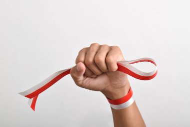 Eller, beyaz arka planda izole edilmiş Endonezya bayrağının bir sembolü olarak kırmızı ve beyaz kurdelelerle sımsıkı sarılmış. Endonezya Bağımsızlık Günü konsepti, 17 Ağustos. Boşluğu kopyala