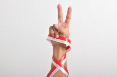Beyaz arka planda Endonezya bayrağı ve barışı simgeleyen kırmızı ve beyaz kurdeleli iki parmağı işaret ediyor. Endonezya Bağımsızlık Günü kavramı 17 Ağustos. Boşluğu kopyala