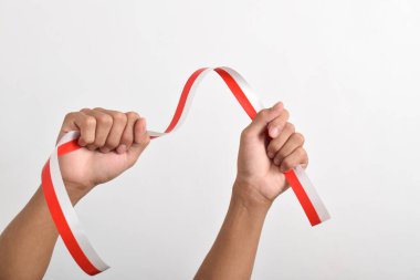 Her iki el de, beyaz arka planda izole edilmiş, kırmızı ve beyaz Endonezya bayrağının sembolü olarak kırmızı ve beyaz kurdeleyi tutuyordu. Endonezya Bağımsızlık Günü konsepti, 17 Ağustos. Boşluğu kopyala
