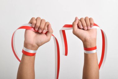 Her iki el de, beyaz arka planda izole edilmiş, kırmızı ve beyaz Endonezya bayrağının sembolü olarak kırmızı ve beyaz kurdeleyi tutuyordu. Endonezya Bağımsızlık Günü konsepti, 17 Ağustos. Boşluğu kopyala