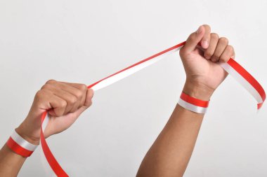 Her iki el de, beyaz arka planda izole edilmiş, kırmızı ve beyaz Endonezya bayrağının sembolü olarak kırmızı ve beyaz kurdeleyi tutuyordu. Endonezya Bağımsızlık Günü konsepti, 17 Ağustos. Boşluğu kopyala