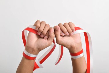 Her iki el de, beyaz arka planda izole edilmiş, kırmızı ve beyaz Endonezya bayrağının sembolü olarak kırmızı ve beyaz kurdeleyi tutuyordu. Endonezya Bağımsızlık Günü konsepti, 17 Ağustos. Boşluğu kopyala