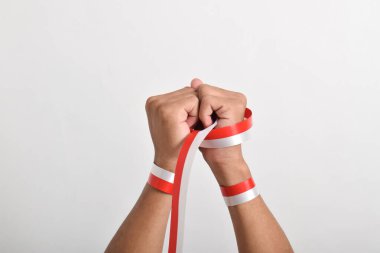 Her iki el de Endonezya bayrağının bir sembolü olarak kırmızı ve beyaz kurdeleyi tutuyor ve beyaz arka planlı Endonezya için umut besliyor. 17 Ağustos 'ta Endonezya Bağımsızlık Günü Konsepti. Kopya Boşluğu