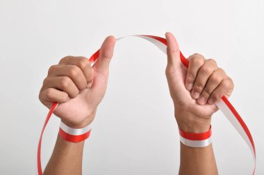 İki el de beyaz arka planda izole edilmiş Endonezya bayrağının sembolü olarak kırmızı ve beyaz kurdele tutuyor. Endonezya Bağımsızlık Günü kavramı 17 Ağustos. Boşluğu kopyala
