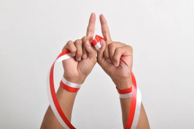 Her iki el de beyaz arka planda kırmızı ve beyaz kurdeleli bir parmağını Endonezya bayrağı ve özgüveninin sembolü olarak gösteriyor. Endonezya Bağımsızlık Günü kavramı 17 Ağustos