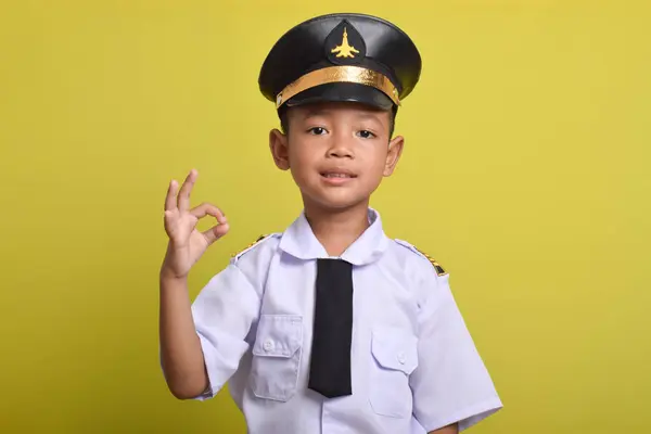 stock image Little Asian boy Airplane pilot isolated on yellow background showing ok sign with fingers. Little boy dreams of becoming an airplane pilot.