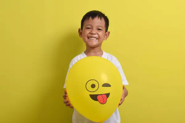 Dil emojisi. Sarı arka planda izole edilmiş, dilini dışarı çıkaran yakışıklı Asyalı çocuk. Kapalı gözlerle alay eden emoji