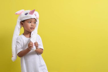 Asyalı küçük çocuk sarı arka planda sevimli bir şapka takıyor. Yakışıklı Asyalı bir çocuğun portresi.