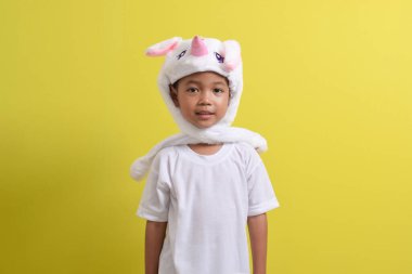 Asyalı küçük çocuk sarı arka planda sevimli bir şapka takıyor. Yakışıklı Asyalı bir çocuğun portresi.