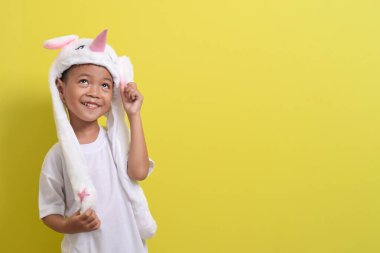 Asyalı küçük çocuk sarı arka planda sevimli bir şapka takıyor. Yakışıklı Asyalı bir çocuğun portresi.
