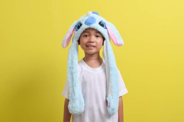 Asyalı küçük çocuk sarı arka planda sevimli bir şapka takıyor. Yakışıklı Asyalı bir çocuğun portresi.