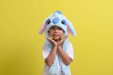 Asyalı küçük çocuk sarı arka planda sevimli bir şapka takıyor. Yakışıklı Asyalı bir çocuğun portresi.