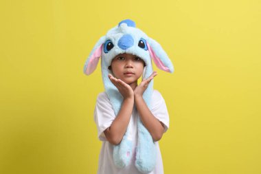 Asyalı küçük çocuk sarı arka planda sevimli bir şapka takıyor. Yakışıklı Asyalı bir çocuğun portresi.