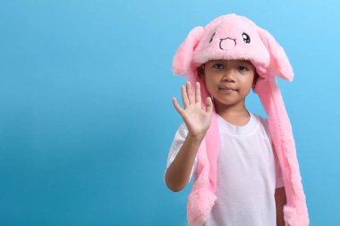 Asyalı küçük çocuk mavi arka planda sevimli bir şapka takıyor. Yakışıklı Asyalı bir çocuğun portresi.