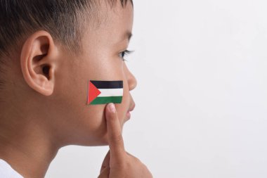 Beyaz arka planda Filistin 'e destek sembolü olarak yanağında Filistin bayrağı olan küçük Asyalı çocuk. Özgür Filistin