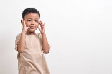 Asyalı bir çocuğun beyaz arka planda mutlu bir şekilde gülümsemesi. Asyalı bir çocuğun portresi