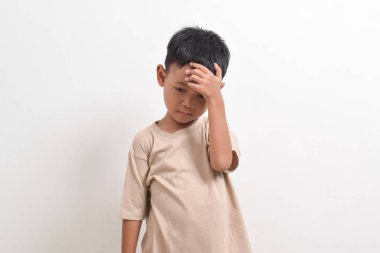 Asyalı çocuk pozu, beyaz arka planda baş ağrısı ve ateş konsepti. Asyalı bir çocuğun portresi