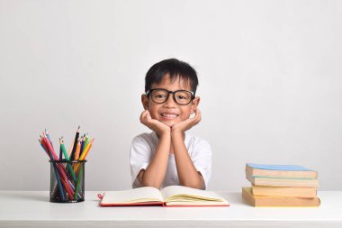 Portrait of an Asian boy studying with a happy expression isolated on a white background clipart