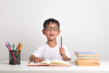 Asyalı bir çocuğun portresi beyaz bir arka planda izole edilmiş mutlu bir ifadeyle elinde kalem tutuyordu.