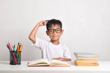 Beyaz bir arka planda izole edilmiş Asyalı bir çocuğun portresi. Düşünen bir yüz ifadesiyle başını tutuyor.