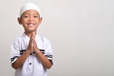 Beyaz arka planda Ramazan kutlaması yapmak için poz veren Asyalı Müslüman çocuk