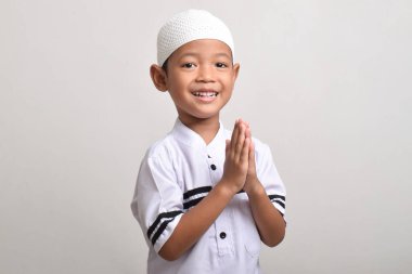 Beyaz arka planda Ramazan kutlaması yapmak için poz veren Asyalı Müslüman çocuğun yan görünüşü