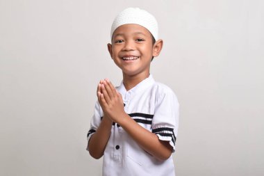 Side view of Asian Muslim boy posing to give Ramadan greetings isolated on white background clipart