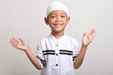 Asian Muslim boy smiling happily to give greetings during the Ramadan celebration with both hands open isolated on a white background clipart