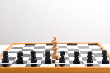 Beyaz arka planda izole edilmiş satranç oyununda beyaz papazın önünde siyah piyonlar. İnsanlar monarşiye karşı..